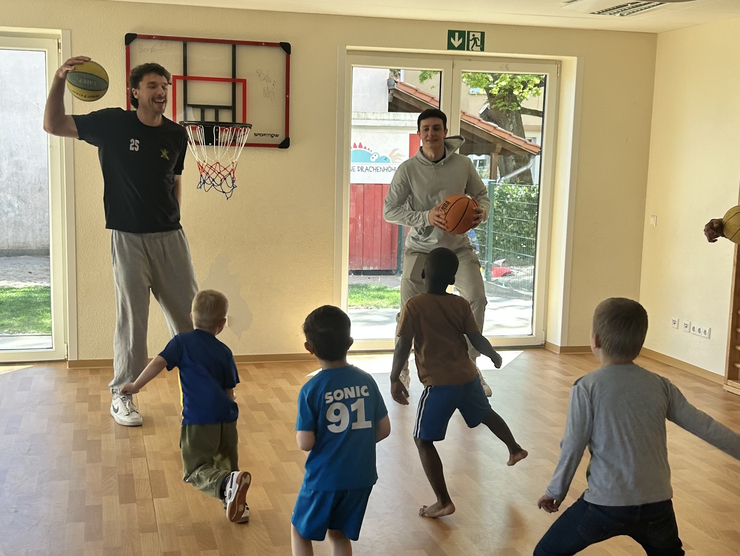 zwei Dragonsspieler in Aktion mit den Kindern