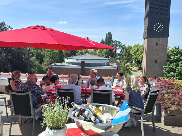 Teilnehmer sitzen auf Dachterrasse Blick auf Kirchturm