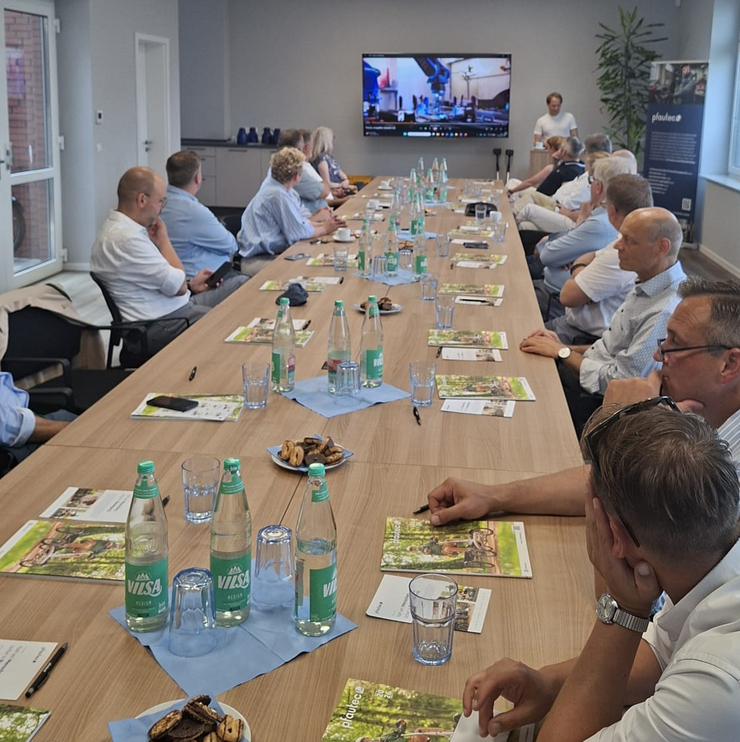 alle sitzen am langen Tisch und schauen Präsentation an
